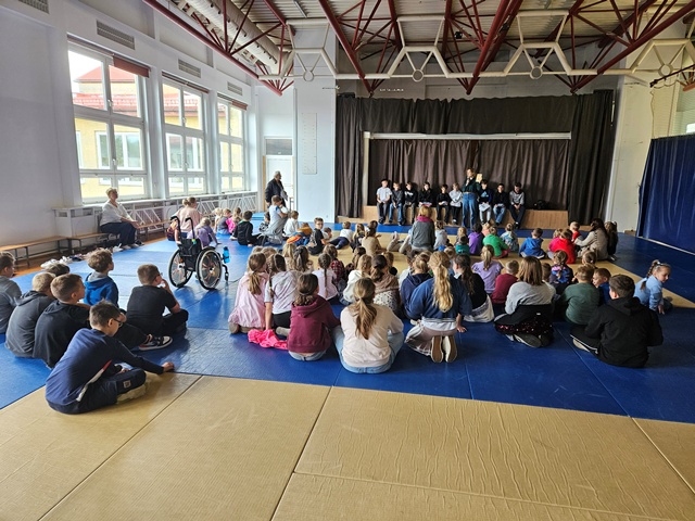uczniowie na auli szkolnej słuchają głośnego czytania