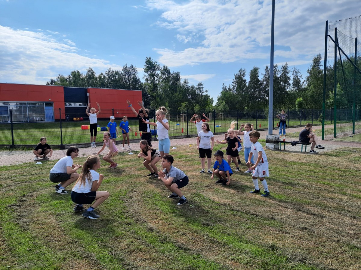 Kadr przedstawia grupę uczniów z klas 1-3 podczas rozgrzewki przed Szkolnym Biegiem Wiosny 2024