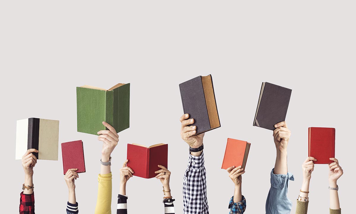Fotografia rąk wyciągniętych do góry z otwartą książką