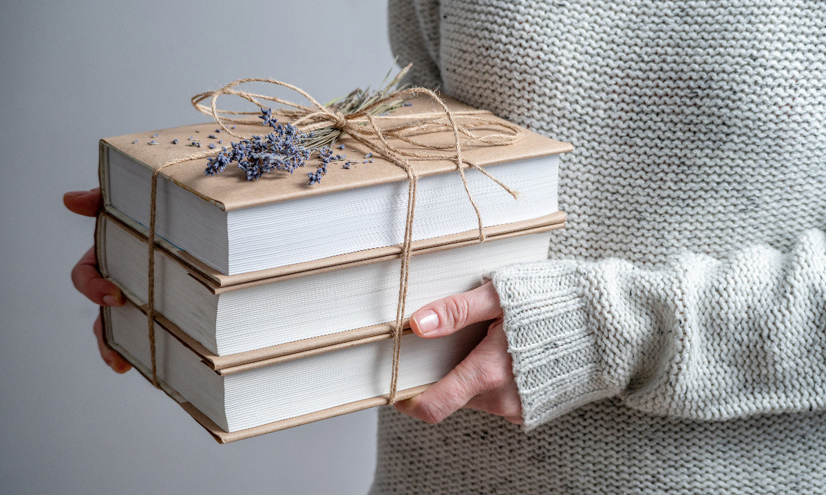 zdjęcie 3 książek przewiązanych sznurkiem w formie prezentu w dłoniach