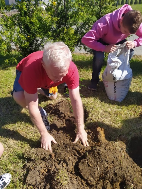 Zdjęcie przedstawia kadr z sadzenia drzewek przez klasę 8a.