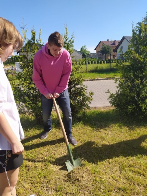 Zdjęcie przedstawia kadr z sadzenia drzewek przez klasę 8a.