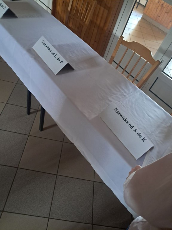 Stół wyborczy nakryty białym obrusem z kartkami oznaczonymi 