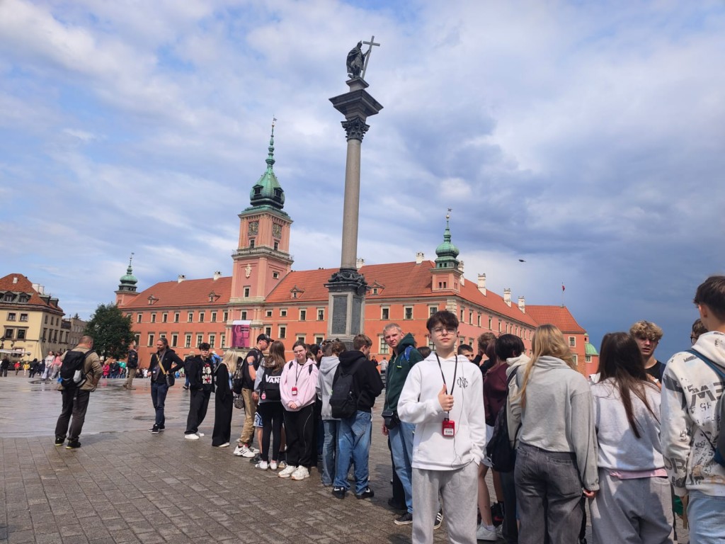 Wycieczka klas 8 do Warszawy 9-11.06.2025. Grupa uczniów przed na rynku przed Zamkiem Królewskim w Warszawie.