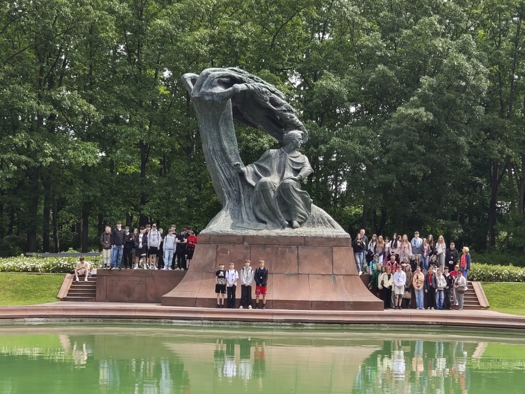 Wycieczka klas 8 do Warszawy 9-11.06.2025. Grupa uczniów pod Pomnikiem Chopina w Łazienkach Królewskich.