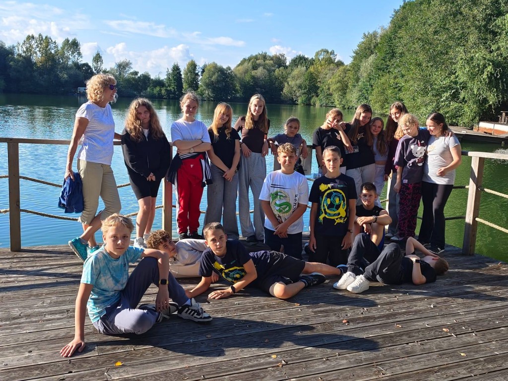 Grupa uczniów na tle jeziora na terenie ośrodka rekreacyjno-konferencyjnego w H2o w Kiczycach. Pamiątkowe zdjęcie.