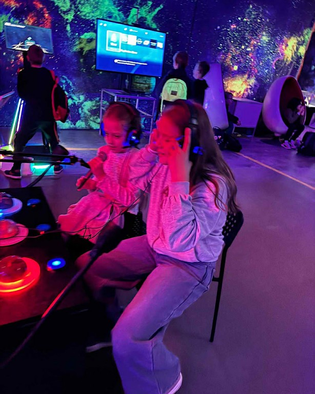 Zdjęcie przedstawia udział uczniów w przeróżnych interaktywnych grach, symulacjach oraz urządzeniach np wysyłających wiadomości w kosmos.