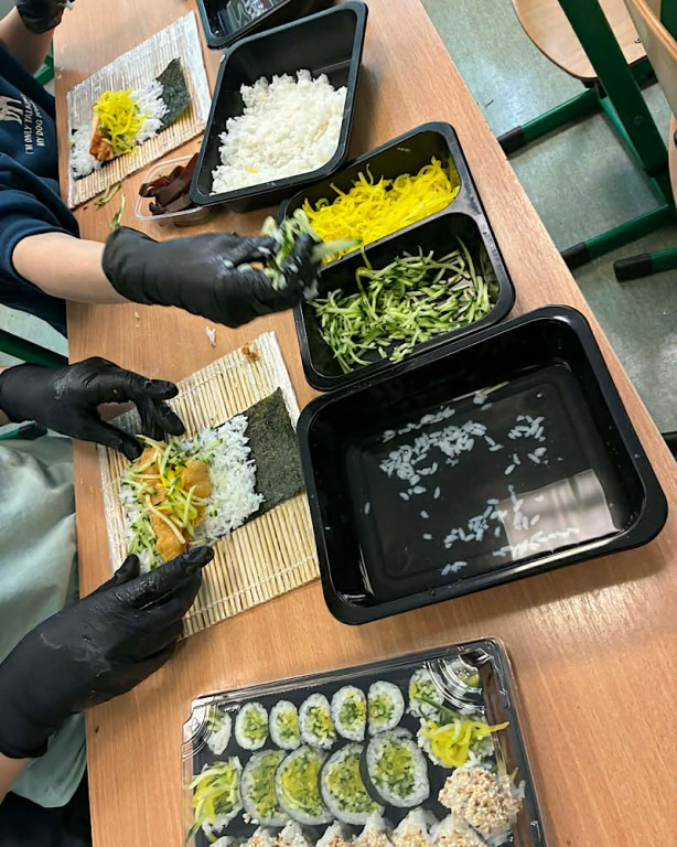 Zdjęcie przedstawia uczniów, którzy własnoręcznie zawijali rolki wypełnione np. warzywami