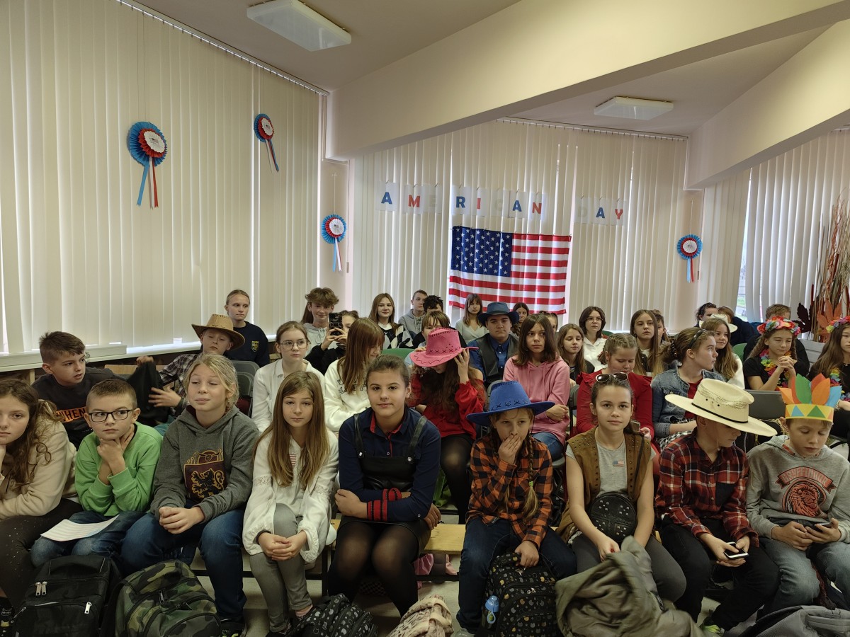 Dzień amerykański w szkole. Grupa uczniów w bibliotece szkolnej podczas uroczystości.