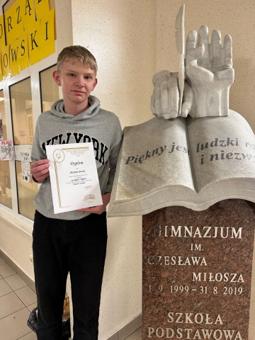 Zdjęcie przedstawia laureata konkursu Przygoda z technika 2025, który trzyma w ręku dyplom