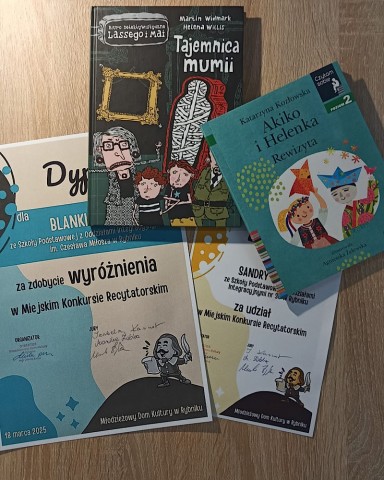 Kadr z konkursu recytatorskiego klas 1-3-zdjęcie przedstawia książki i dyplomy.