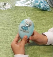 Zdjęcie przedstawia jajko zdobione techniką decoupage trzymane w rękach dziecka.