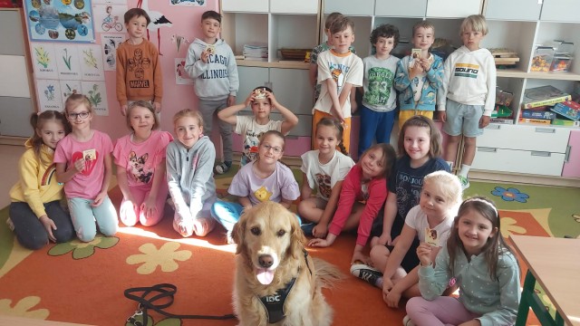 Zdjęcie przedstawia grupę dzieci  po zajęciach z psem, z elementami dogoterapii w szkole