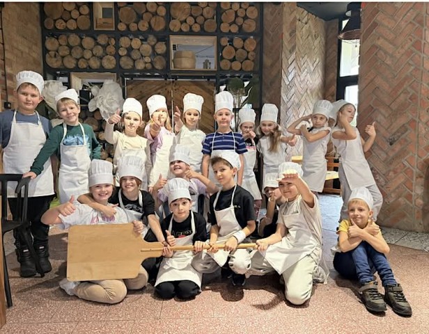 Zdjęcie przedstawia uczniów w czasie warsztatów z pieczenia pizzy, 