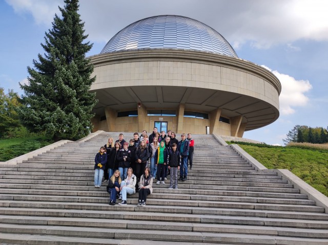 Uczniowie klasy siódmej na schodach przed budynkiem Planetarium Śląskiego w Chorzowie.